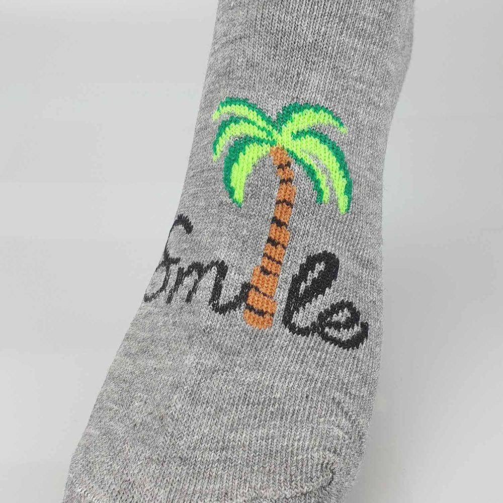 detalj strumpa med en palm och texten"smile"
